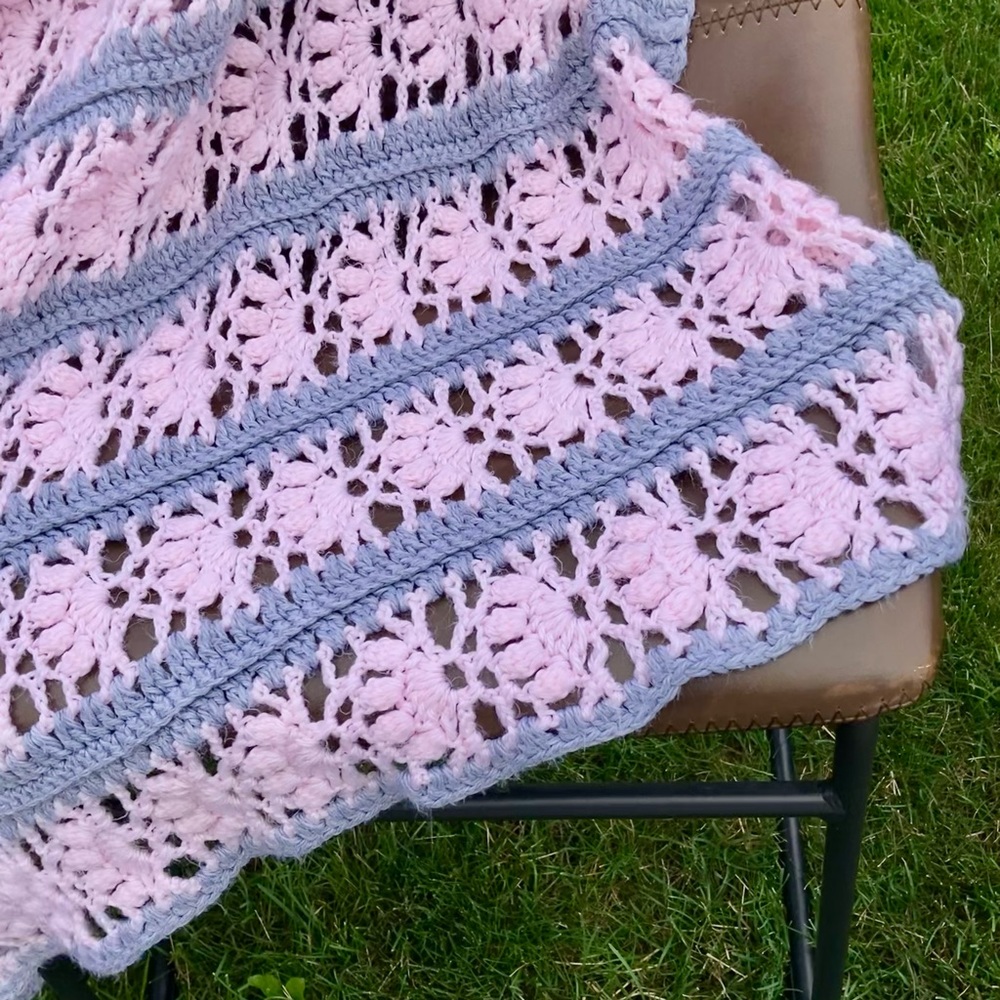 Crocheted baby blanket in soft pink and medium gray.